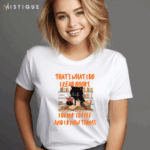 Bijela majica s printom crnog mačka okruženog knjigama i šalicama kave, uz tekst "That's what I do. I read books, I drink coffee, and I know things."