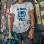 Bijela majica s plavim logom NK Rijeka 2025 i ilustracijom trofeja.